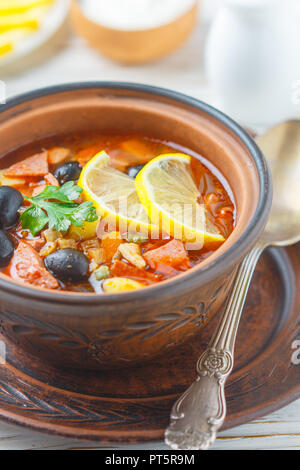 Traditionelle russische Suppe Solyanka mit Fleisch, Wurst, Gemüse, Kapern, Essiggurken und Oliven mit Zitrone, Gewürzen und Gewürzen. Mit saurer Crea serviert. Stockfoto