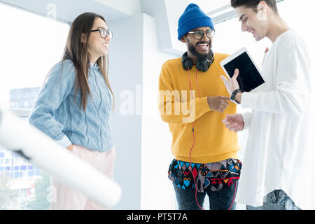 Positiv begeistert Junge multi-ethnischen Freunde in Freizeitkleidung zusammen lachen, während im Büro Lobby zu stehen und sich zu unterhalten Stockfoto