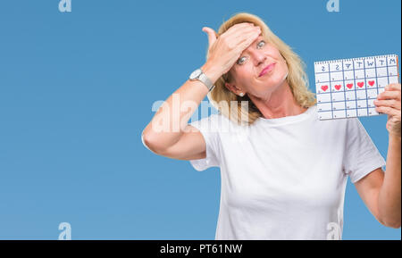 Mittleres Alter blonde Frau mit Menstruations Kalender ver isoliert Hintergrund mit der Hand auf den Kopf hob, mit Scham und Überraschung Gesicht schockiert, wütend Stockfoto