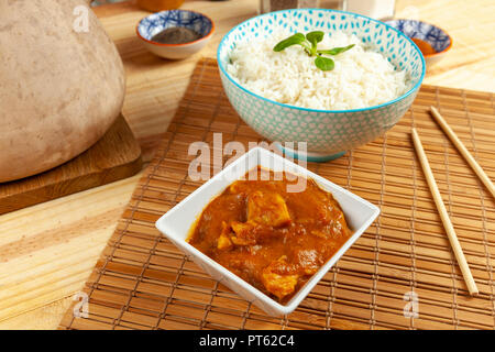 Teil der chinesischen Chicken Curry und eine Schüssel Reis auf einem Bambus tisch Matte mit Essstäbchen Set Stockfoto