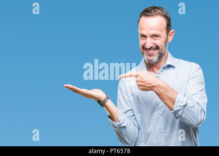 Mittleres Alter hoary Senior Business Mann über isolierte Hintergrund erstaunt und lächelt in die Kamera während der Präsentation mit Hand und zeigte mit dem Finger. Stockfoto