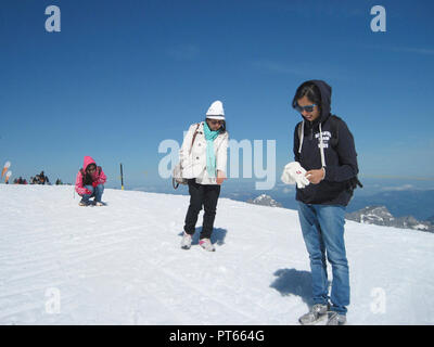 Junge indische Touristen SPIELEN MIT SCHNEE AUF DEM TITLIS, Schweiz Stockfoto