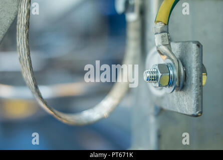 Eine Erdungsschraube mit Kabelschuh an einem metallstab in einer industriellen Anlage Stockfoto