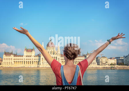 Glückliche junge Mädchen Anheben der Arme in von der Budapester Parlament, Ungarn Stockfoto