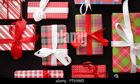Blick von oben auf die aufgewickelte Weihnachtsgeschenke auf dem schwarzen Hintergrund Stockfoto