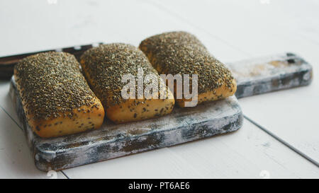 Nahaufnahme von Vollkornbrot mit Samen auf einem rustikalen Holzbrett Stockfoto