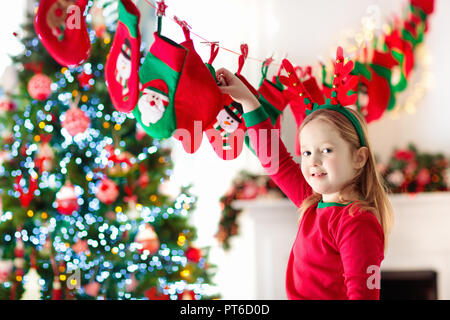 Kinder öffnung Weihnachtsgeschenke. Kind auf der Suche nach Süßigkeiten und Geschenke im Adventskalender auf Winter morgen. Geschmückten Weihnachtsbaum für Familie mit ch Stockfoto