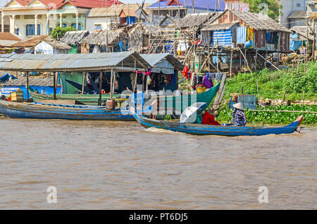 Siem Reap, Kambodscha - 11. April 2018: Drei Frauen Rudern ein long-tail Holz- Boot entlang der Ufer des Tonle Sap See vor einem Gedrechselten Dorf Stockfoto