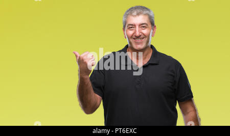 Gut aussehender älterer Mann über isolierte Hintergrund lächelnd mit glücklichen Gesicht und zeigt auf die Seite mit dem Daumen nach oben. Stockfoto