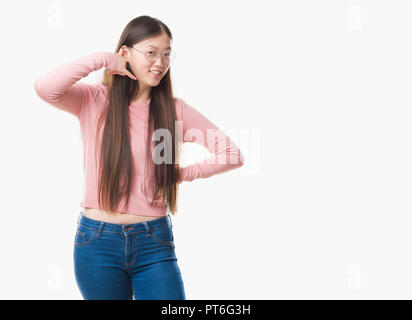 Junge chinesische Frau über isolierte Hintergrund Brille lächelnd tun Telefon Geste mit der Hand und der Finger wie im Gespräch am Telefon. Communic Stockfoto