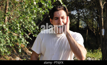 Junge Mann in der Natur leiden unter Zahnschmerzen Stockfoto