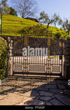 Italien, Bellagio, Comer See, eine Bank neben einem Bellagio, Italy-April 1, 2018: The Mansion Tor an I Giardini di Villa Melzi Stockfoto