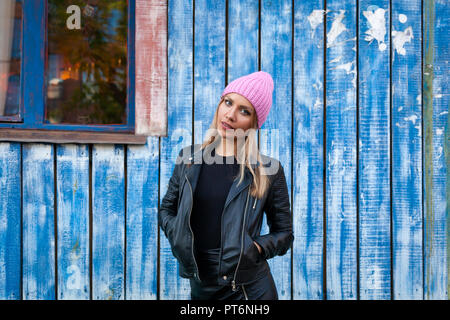 Portrait Studentin auf hellen Hintergrund. Schöne moderne urbane junge Frau tragen rosa Stricken hat Lächeln, Blick in die Kamera und engoy Herbst Stockfoto