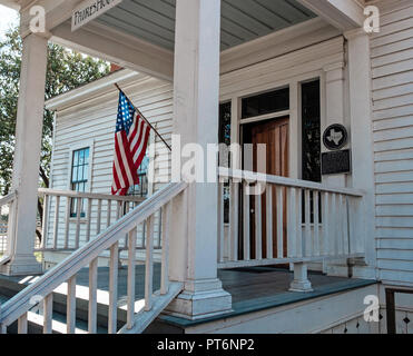 Eingang des Weiß geschuppt Haus mit Stufen. Älteste Haus in Mckinney Texas stehend, Kastanie Square. Build 1854. Amerikanische Flagge auf erweiterten Pol Stockfoto