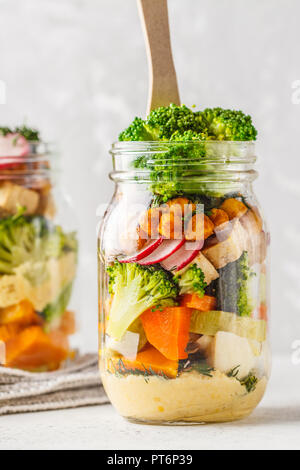 Gesunde hausgemachte Mason Jar-Salat mit gebackenem Gemüse, Hummus, Tofu und Kichererbsen. Gesunde Ernährung, Entgiftung, sauber Essen oder vegane Konzept. Stockfoto