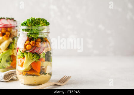 Gesunde hausgemachte Mason Jar-Salat mit gebackenem Gemüse, Hummus, Tofu und Kichererbsen. Gesunde Ernährung, Entgiftung, sauber Essen oder vegane Konzept. Stockfoto