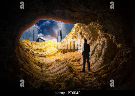 Unternehmer stehen in einer Höhle und blickt auf die Hochhäuser am Ende Erfolg Suche Konzept Stockfoto