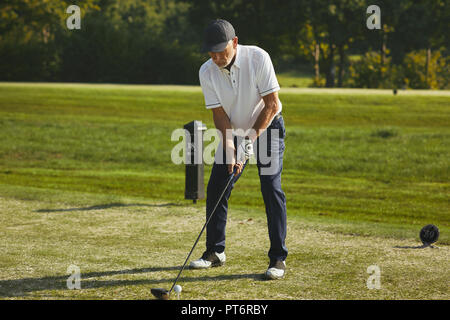 Sportliche älterer Mann weg abzweigen mit seinem Treiber während einer Runde Golf spielen an einem sonnigen Tag Stockfoto