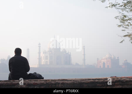 Majestic Taj Mahal die Wunder der Welt und der Stolz von Indien im Winter morgen weichen warmen Licht mit Dunst und durch einen männlichen Touristen beobachtet Stockfoto