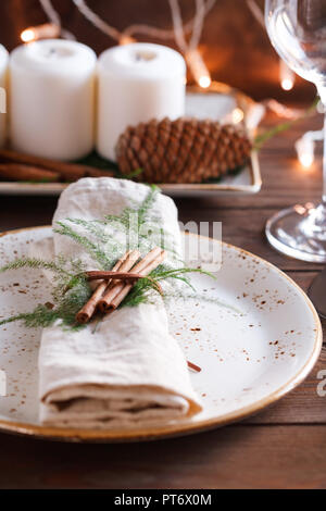 Bettwäsche Serviette dekoriert Zimtstangen und Pflanzen auf einer Keramikplatte. Das Konzept der Weihnachten und Thanksgiving Dinner und dekorieren Tabelle Einstellungen. Stockfoto