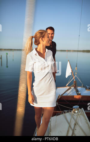 Junge Frau, die ihren Mann an der Hand auf dem Deck des Bootes und genießen Sie den Tag gemeinsam Segeln Stockfoto