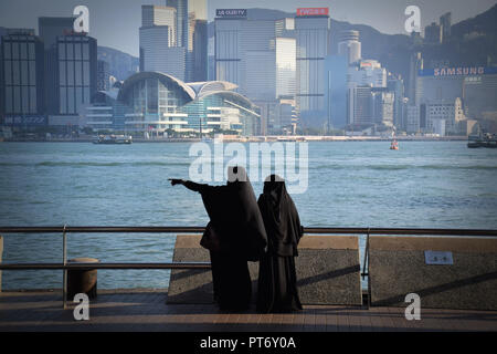 Mädchen gekleidet mit Burka vor der Skyline von Hong Kong Island vom Tsim Sha Tsui Promenade in Hongkong, China Stockfoto