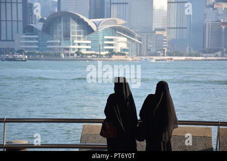 Mädchen gekleidet mit Burka vor der Skyline von Hong Kong Island vom Tsim Sha Tsui Promenade in Hongkong, China Stockfoto