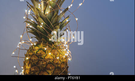 Nahaufnahme von Ananas mit Weihnachten Lichterkette mit Kopie Raum, Grußkarte Konzept auf grauem Hintergrund banner Stockfoto