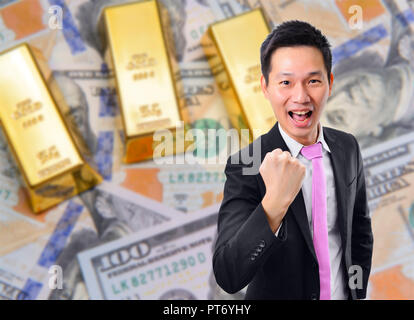 Happy Geschäftsmann mit Goldbarren und Dollar banknote Hintergrund Stockfoto