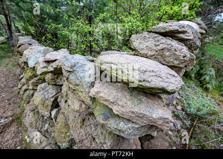 Die Ecke eines alten trockenen Steinmauer von zufälligen Felsen mit grünen Pflanzen im Frühling, Bulgarische Landschaft, Rhodopen Stockfoto