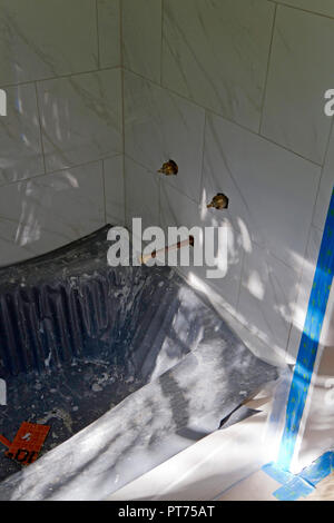 Badewanne und Fliesen Einbau in Fortschritte mit neuen Fliesen, Armaturen, Badewanne schutz Matte, und blau Tape Stockfoto