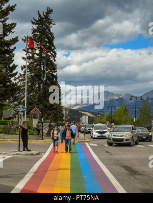 JASPER, AB, Kanada - Juni 2018: Menschen zu Fuß über eine Straße in Jasper auf einem Zebrastreifen in den Farben des Regenbogens bemalt. Stockfoto