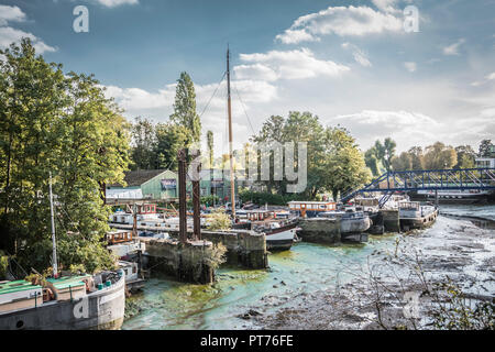 John's Boat Works Ltd,- bunte Hausboote, die auf Lot's Ait an der Themse gegenüber dem Watermans Arts Center, Brentford, London, Großbritannien repariert werden Stockfoto