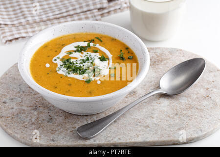 Kürbiscremesuppe mit saurer Sahne und Petersilie auf einem rustikalen Tisch Stockfoto