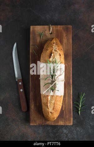 Frische hausgemachte Brot mit Rosmarin auf rustikalen Holzmöbeln Hintergrund, Ansicht von oben, kopieren. Sourdough mini Baguette. Stockfoto