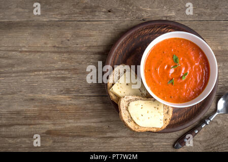 Tomatensuppe mit Brot und Käse auf Holztisch, Ansicht von oben, kopieren. Hausgemachten Tomatensuppe in der Schüssel. Stockfoto