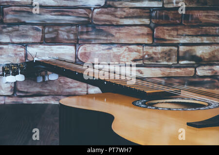 Akustik Gitarre liegt auf einer hölzernen Tisch gegen die Wand. Von der Seite. Stockfoto