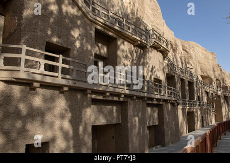 Boardwalk vor nummeriert Höhlen am Mogao Grotten oder Höhlen der Tausend Buddhas, Dunhuang, Gansu, China. Stockfoto