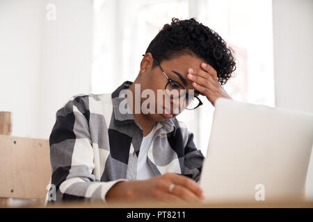 Amerikanische Frau sitzt mit Laptop im Büro umgekippt Stockfoto