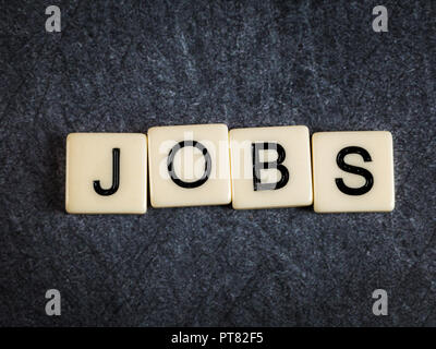 Schreiben Fliesen auf schwarzem Schiefer Hintergrund Rechtschreibung Jobs Stockfoto