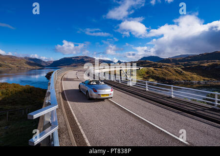 Ein Cabrio Sportwagen über die Kylesku Brücke, Nordküste 500 Sutherland, Highland, Schottland, UK fahren Stockfoto