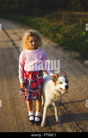 Curly blonde Mädchen und großer Hund Stockfoto