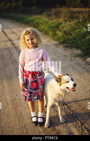 Curly blonde Mädchen und großer Hund Stockfoto