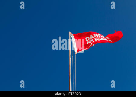 Gefahr für das Schwimmen. Rotes Dreieck Flagge am Strand winkt oben blauer Himmel Stockfoto