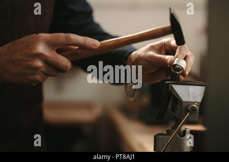 In der Nähe von älteren weiblichen Juwelier, ein silberner Ring mit Werkzeugen. Schmuck Designer gestalten einen Ring an ihrem Workshop. Stockfoto