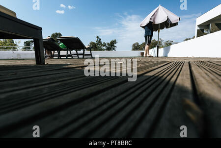 Mann, der mit seinem Kopf in den Regenschirm und Frau zurück in die Hängematte mit blauem Himmel Hintergrund sitzen Stockfoto