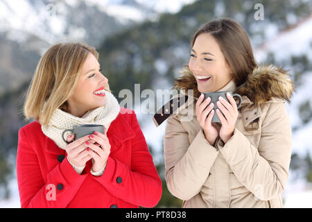 Zwei glückliche Frauen Reden halten Kaffeetassen im Winter Urlaub in den Bergen Stockfoto