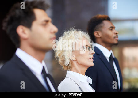 Schwere zielgerichtete Business Team zuversichtlich in die Ferne und stehen im Freien suchen, sie sind stolz auf die herausragenden Leistungen der Firma Stockfoto