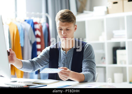 Junge Designer mit Farbmuster set vergleichen mit denen online während der Arbeit Stockfoto