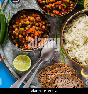 Vegan curry mit grünen Erbsen und Basmatireis auf einem blauen Tisch Tablett serviert, gesunde indische Speisen Stockfoto